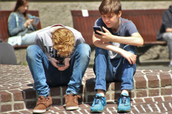 Twee Jongens Met Smartphone In De Hand Zittend Op Speelplaats Rh