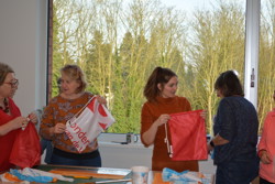 Groepje vrouwen bekijkt samen turnzakjes die ze vasthouden