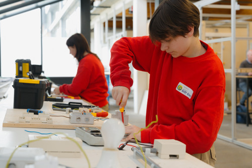 Jongen en meisje werken in een schoolwerkplaats aan een elektrische installatie