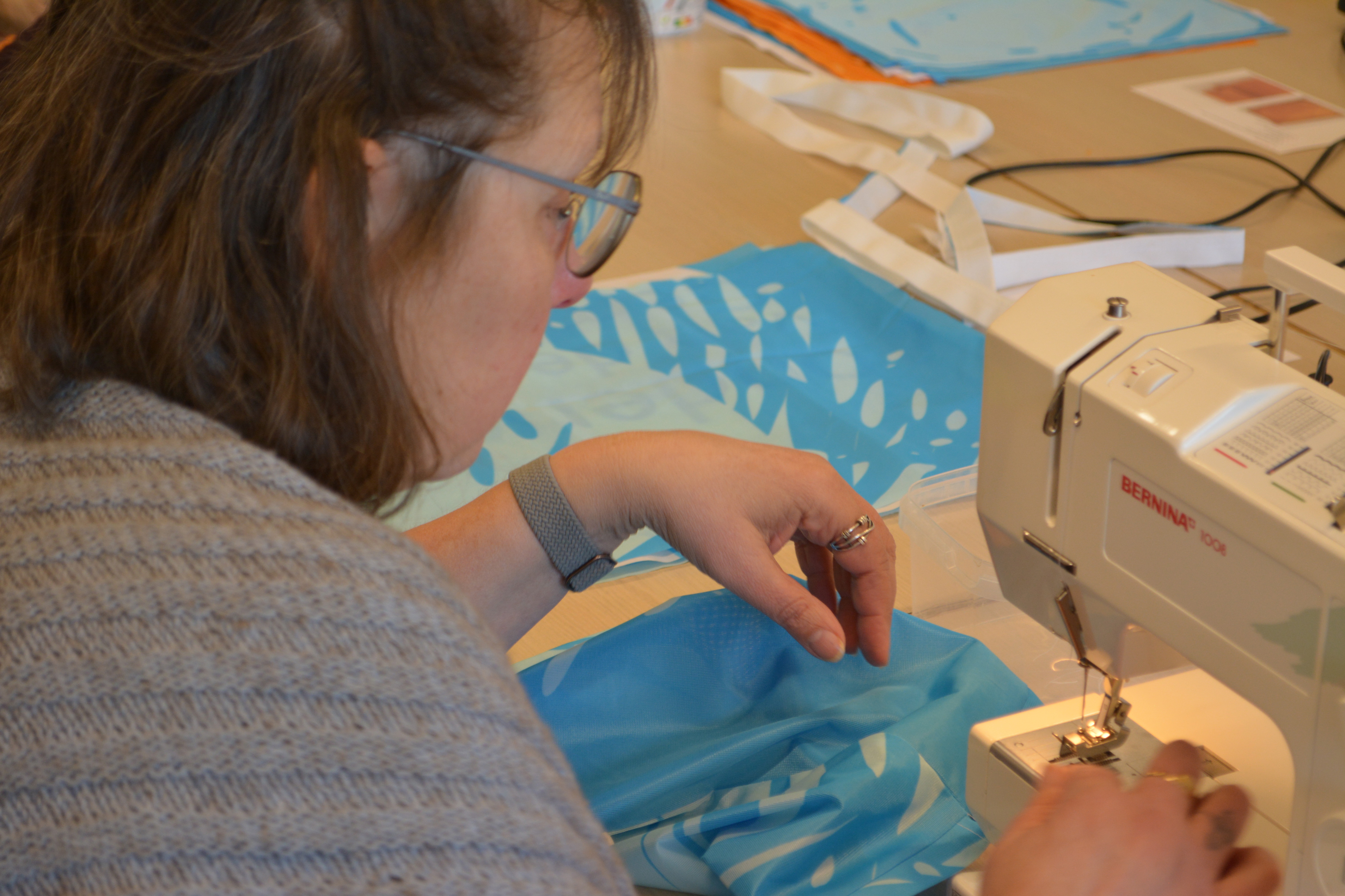 Vrouw aan naaimachine verwerkt blauwe vlag