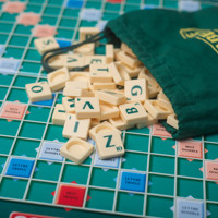 Scrabble spelbord waarop een zakje ligt waar speelblokjes met letters uitrollen