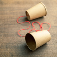 Twee kartonnen bekertjes met een touw tussen als communicatiemiddel