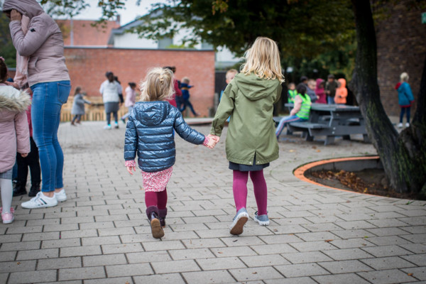 Twee Meisjes Op Speelplaats Hand In Hand En Op De Rug Gezien