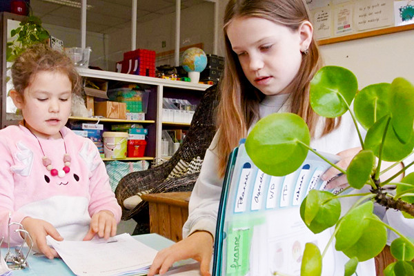 Twee meisjes basisschool bladeren door een map